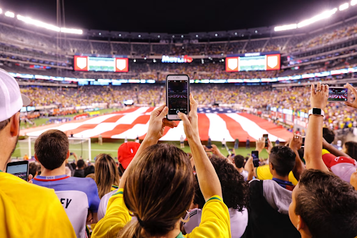 girl-fan-holding-up-phone-at-stadium